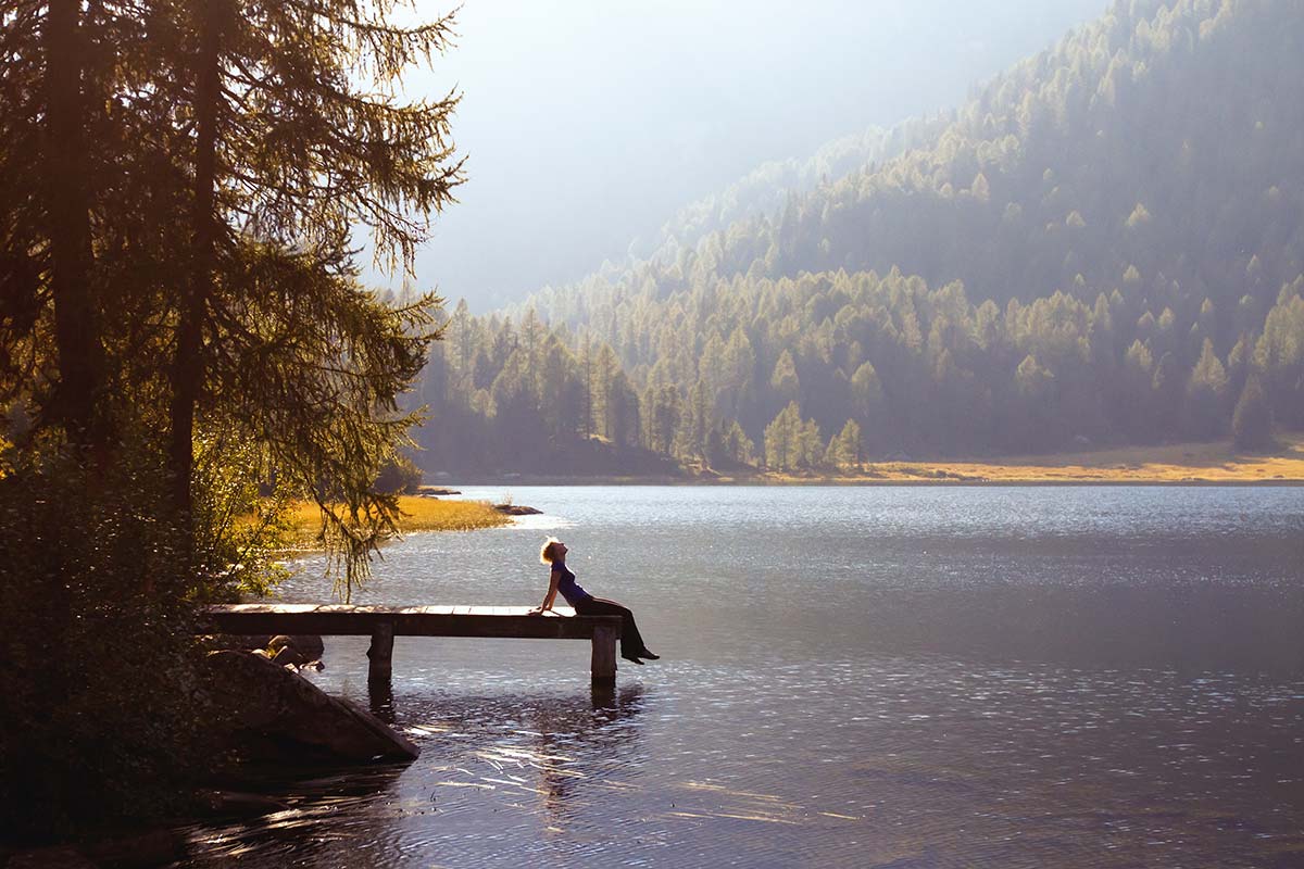 Person on a dock overlooking a lake and forested hills.